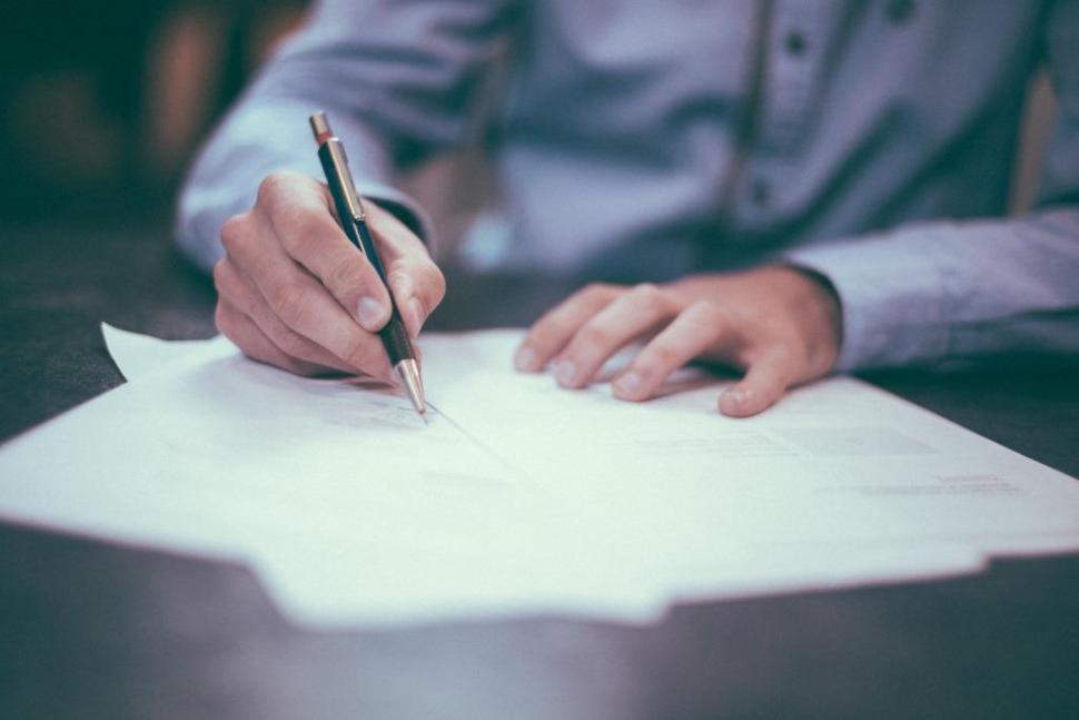 Someone completing an application form on a shiny desk