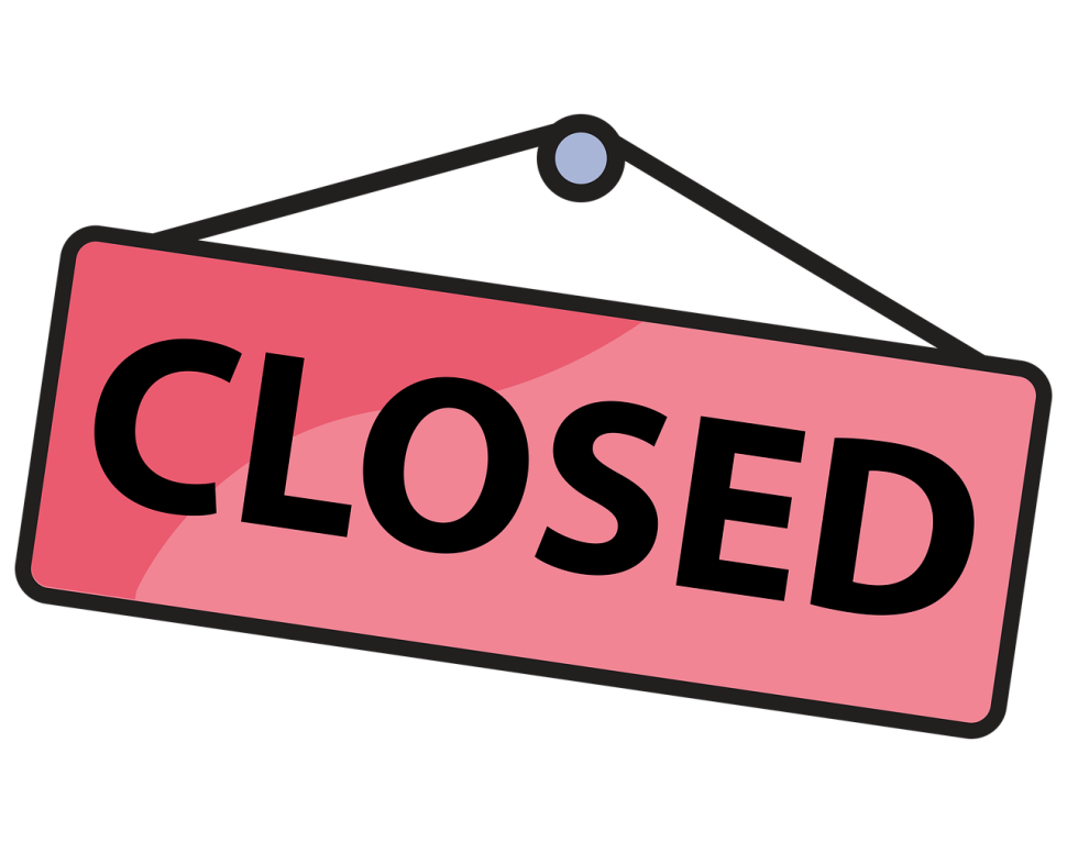 A traditional shop door sign saying "closed": black text on pink