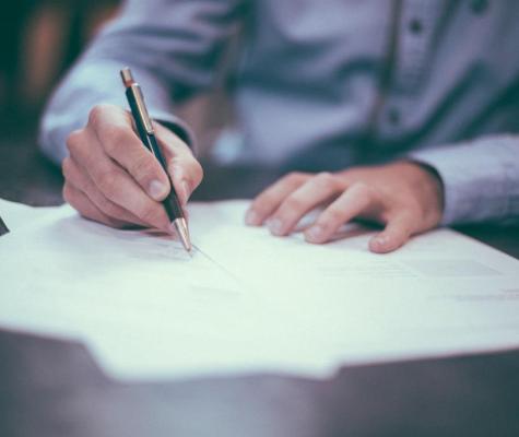 Someone completing an application form on a shiny desk