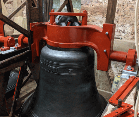 Large church bell hanging on bell frame in church tower